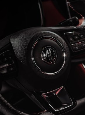 Close-up of an MG car steering wheel with control buttons.