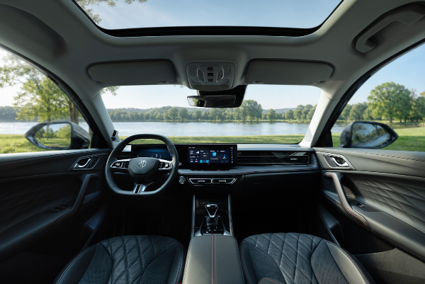 Car interior with a steering wheel, infotainment display, and black quilted seats.