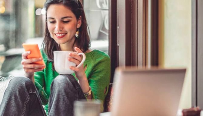 Person on their phone holding a mug