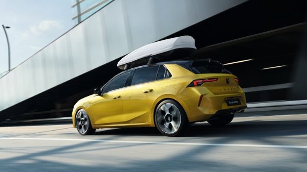 Yellow car with a roof box driving on a road, viewed from the rear side.