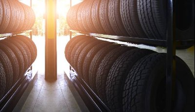 Rows of stacked tyres on racks with sunlight shining in.